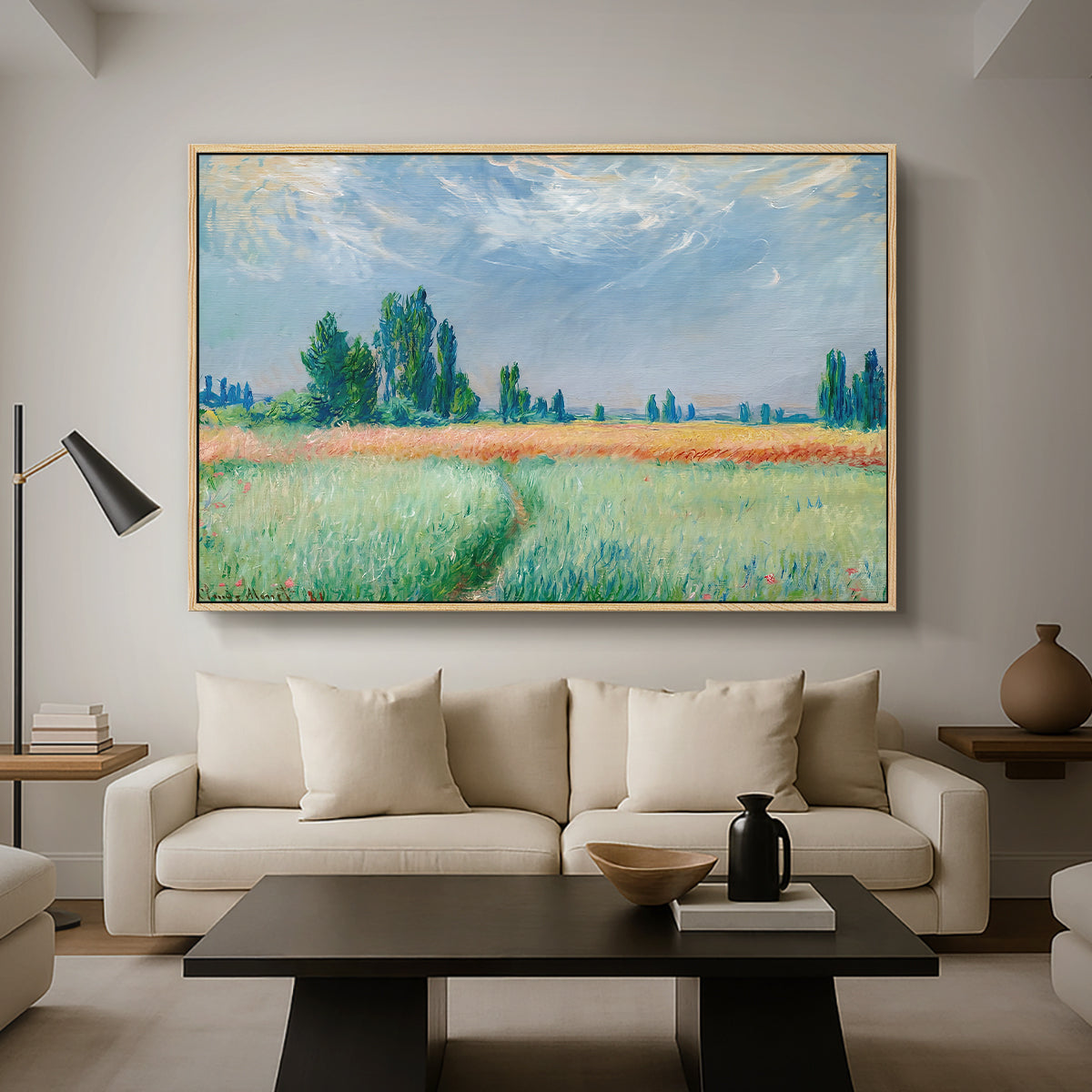 The Wheat Field (Champ de Blé), 1881 by Claude Monet as a natural wood floater framed canvas featuring a golden wheat field stretching across landscape under soft sky, displayed above a sofa in a modern living room.