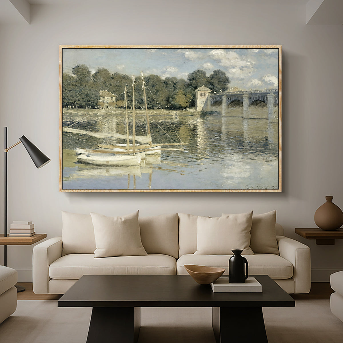 The Bridge at Argenteuil, 1874 by Claude Monet as a natural wood floater framed canvas featuring a bridge spanning river with sailboats and reflections in water, displayed above a sofa in a modern living room.