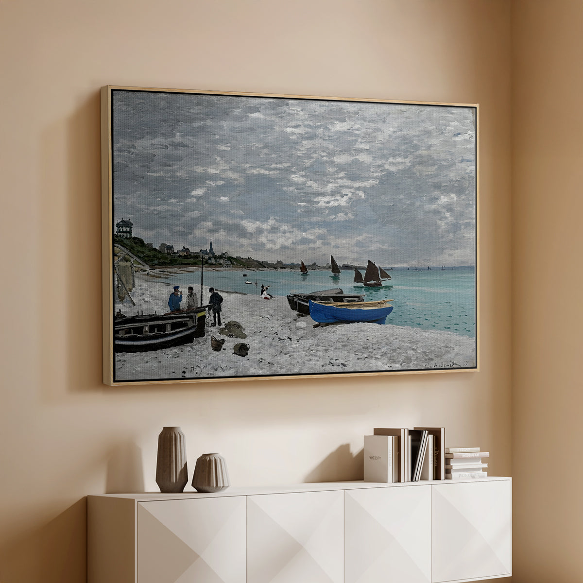 Natural wood floater framed canvas of The Beach at Sainte-Adresse, 1867 by Claude Monet, featuring a lively beach scene with people overlooking water and ships above a console cabinet in a minimalist entryway.