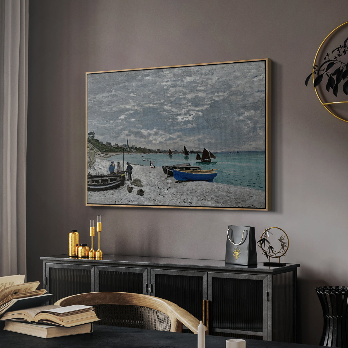 The Beach at Sainte-Adresse, 1867 by Claude Monet in a natural wood floater framed canvas featuring a coastal landscape with sailboats and visitors on cliffside, displayed above a desk in a dark home office interior.