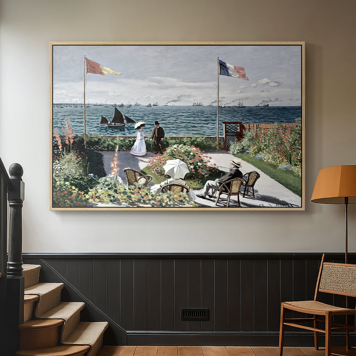 Natural wood floater framed canvas featuring a landscaped terrace with figures and flags near shoreline, displayed in a hallway near a staircase.