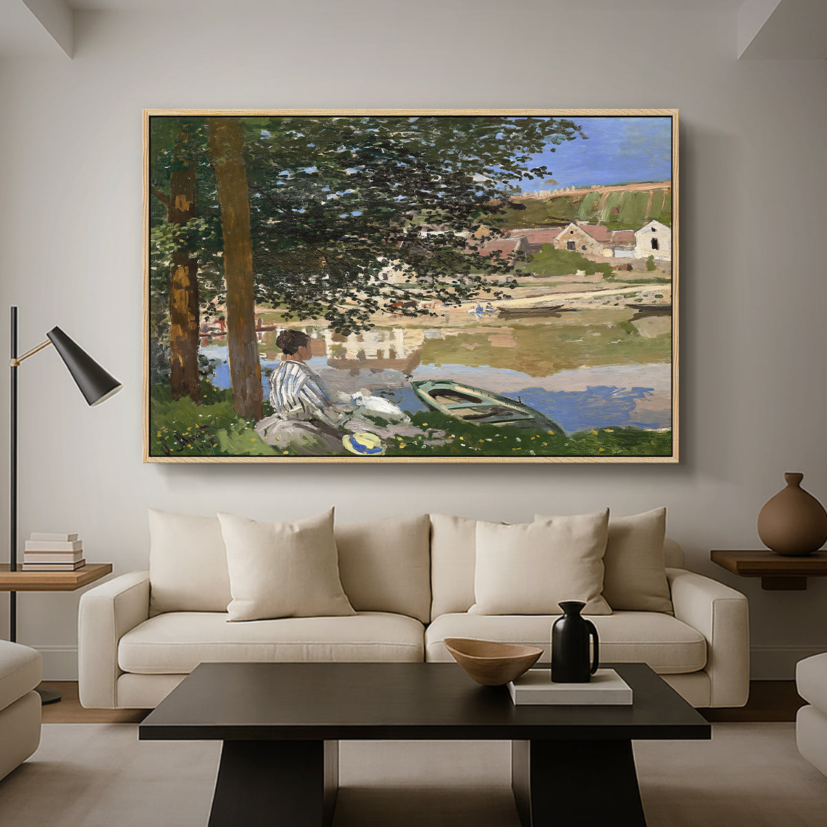 On the Bank of the Seine, Bennecourt, 1868 by Claude Monet as a natural wood floater framed canvas featuring a woman and child seated along riverbank beneath trees in soft daylight, displayed above a sofa in a modern living room.