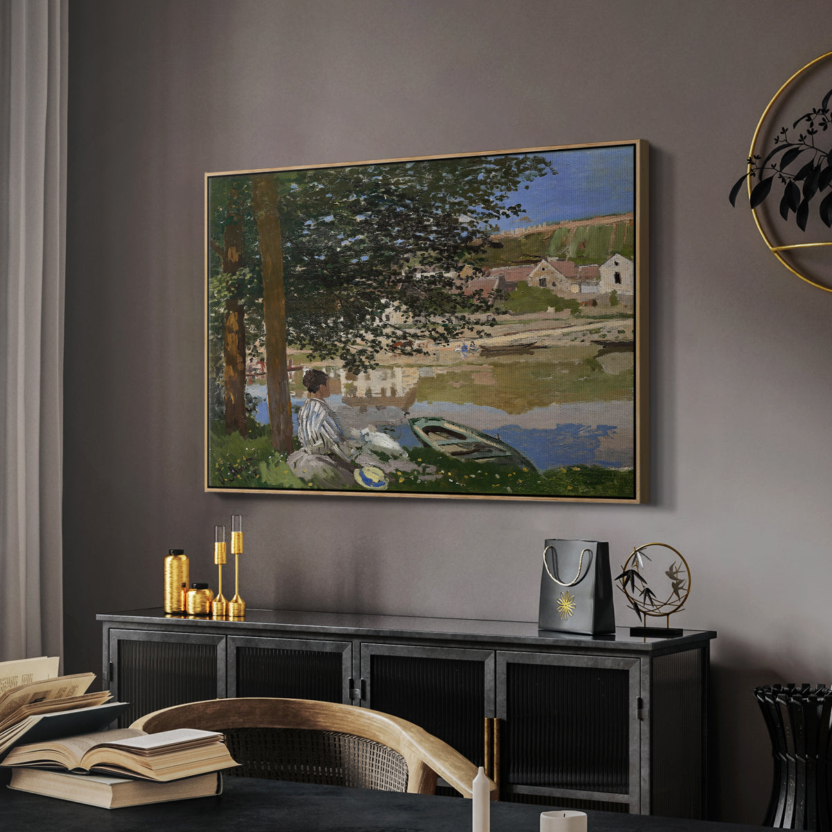 On the Bank of the Seine, Bennecourt, 1868 by Claude Monet in a natural wood floater framed canvas featuring an impressionist landscape with people relaxing along the Seine, displayed above a desk in a dark home office interior.