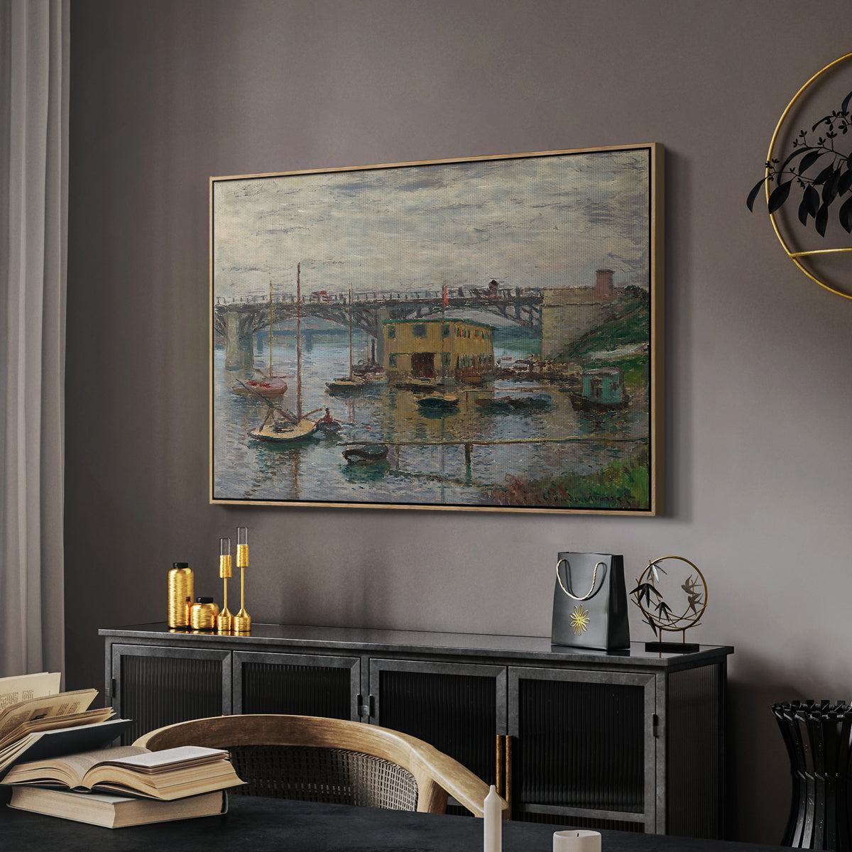 Bridge at Argenteuil on a Gray Day, c. 1876 by Claude Monet in a natural wood floater framed canvas featuring a calm water scene with bridge fading into cloudy sky, displayed above a desk in a dark home office interior.