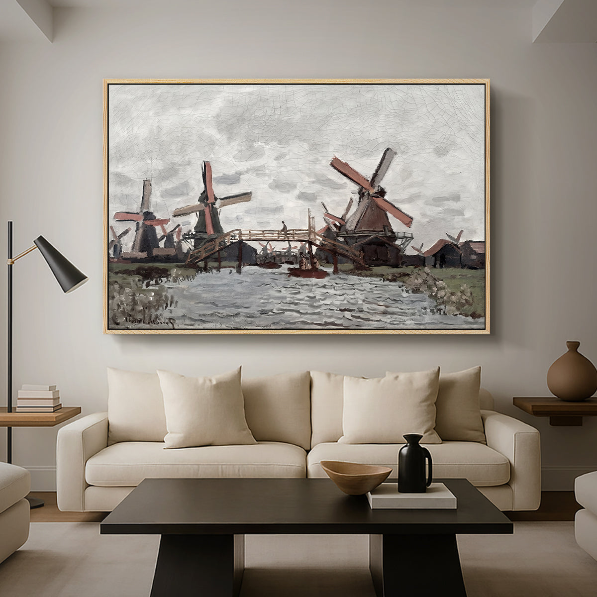 Windmills near Zaandam, 1871 by Claude Monet as a natural wood floater framed canvas featuring windmills standing beside water under open sky in rural landscape, displayed above a sofa in a modern living room.