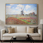 Tulip Fields with the Rijnsburg Windmill, 1886 by Claude Monet displayed in a natural wood floater framed canvas above a sofa in a clean living room.