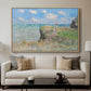 The Cliff Walk at Pourville, 1882 by Claude Monet displayed in a natural wood floater framed canvas above a sofa in a clean living room.