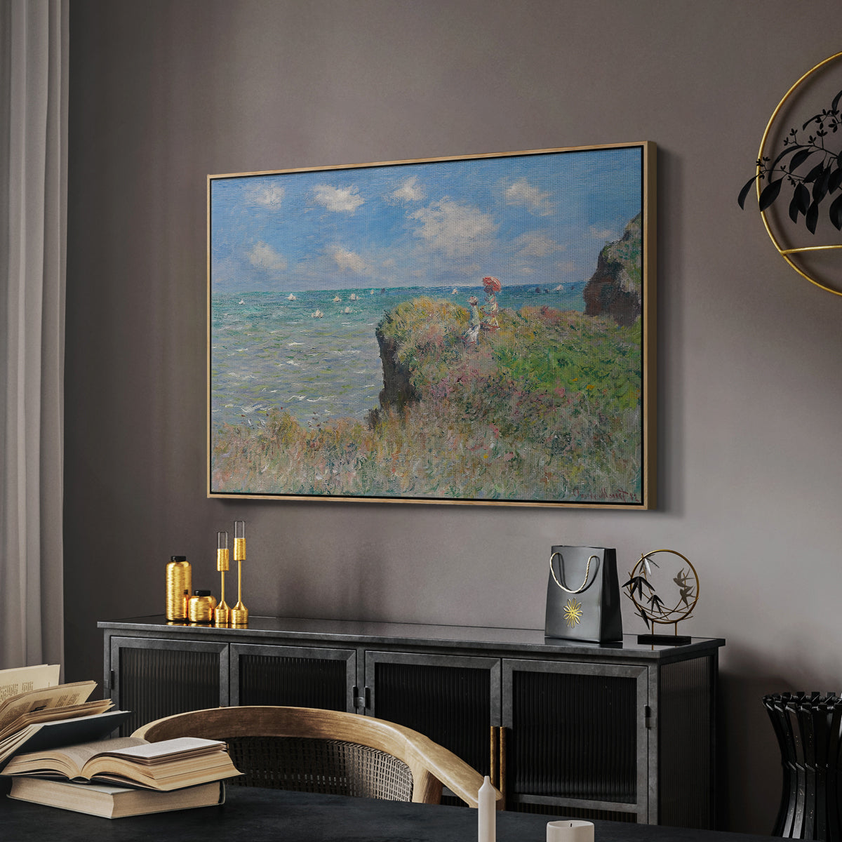 The Cliff Walk at Pourville, 1882 by Claude Monet in a natural wood floater framed canvas featuring a coastal cliff scene with grass, wind, and expansive sea view, displayed above a desk in a dark home office interior.
