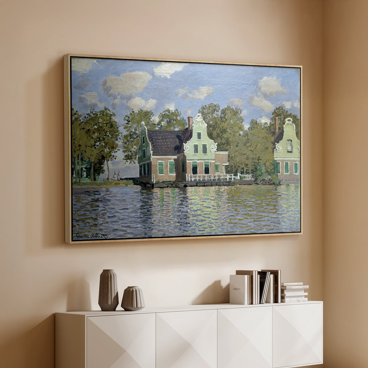 Natural wood floater framed canvas of Houses on the Zaan River at Zaandam, 1871 by Claude Monet, featuring an impressionist riverside village with colorful buildings above a console cabinet in a minimalist entryway.