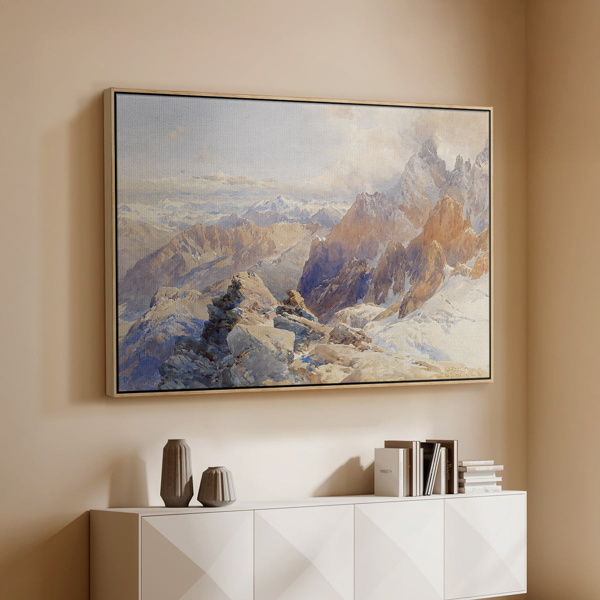 Natural wood floater framed canvas of Col du Géant, 1903 by Edward Theodore Compton, featuring a high mountain landscape featuring dramatic ridges and glacier terrain above a console cabinet in a minimalist entryway.