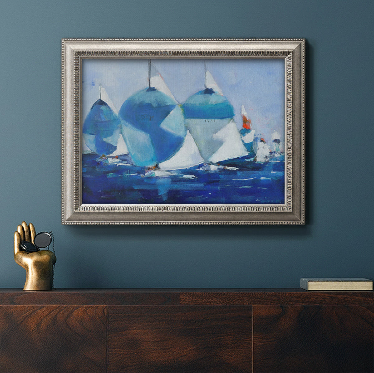 Coastal nautical watercolor painting in an ornate vintage silver frame displayed in a dark-toned interior setting.